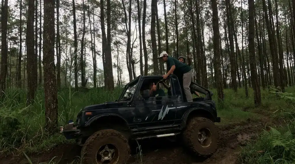 Jeep 4x4 hardtop biru sedang melintasi jalur berlumpur offroad Batu Malang