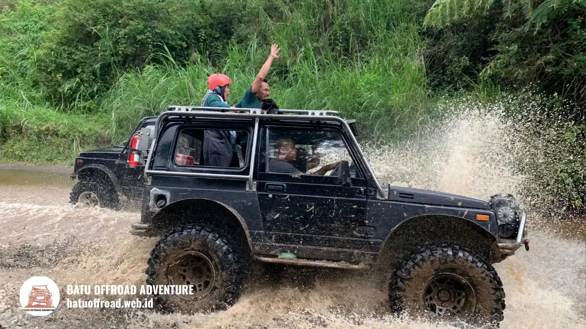 Jeep dengan peserta sedang melintasi jalur berlumpur ekstrem dengan percikan lumpur tinggi
